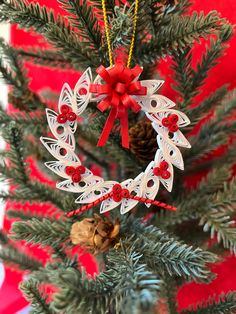 a christmas ornament hanging from a tree with pine cones and red bows on it