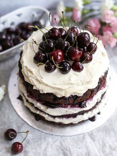 a cake with white frosting and cherries on top