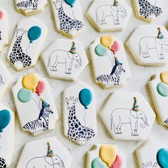 decorated cookies with animals, giraffes and balloons are arranged on a table