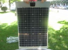 a man standing next to a solar panel in the grass