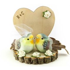 two small birds sitting on top of a tree stump next to a heart shaped sign