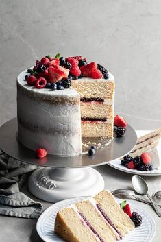 there is a cake with berries on it and two slices missing from the cake plate