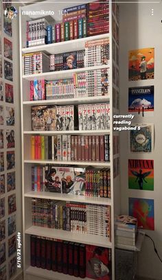 a book shelf filled with lots of books next to a wall covered in comic books