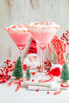 two glasses filled with candy canes and topped with whipped cream, surrounded by christmas decorations