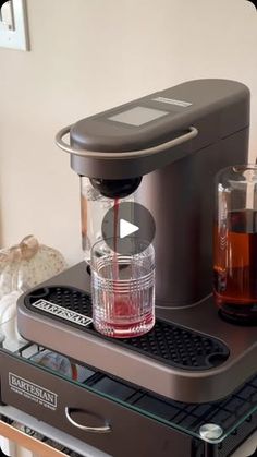 an espresso machine is being used to make coffee on the counter top with two glasses next to it