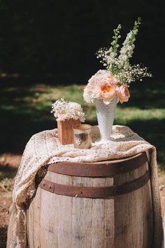 a vase with flowers sitting on top of a wooden barrel