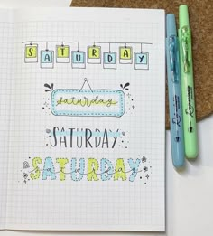 an open notebook with the words saturday written in cursive writing and two markers