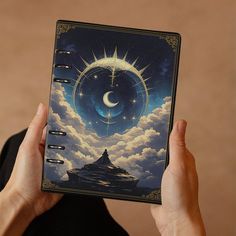 a person holding up a spiral notebook with an image of the moon