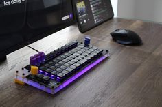 a computer keyboard sitting on top of a wooden desk next to a mouse and monitor