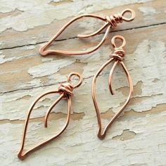 two pairs of copper earrings sitting on top of a wooden table