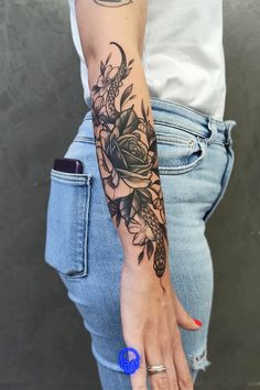 a woman's arm with flowers on it and a blue ring in the middle