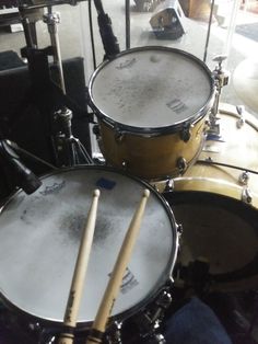 two drums are sitting next to each other in front of a drum set on the floor