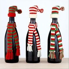 three wine bottles with hats and scarfs on them