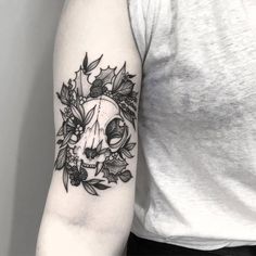 a woman's arm with a skull and flowers tattoo on the left upper arm