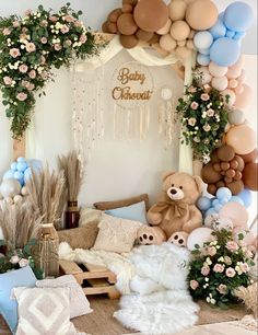 a teddy bear sitting in front of balloons and flowers