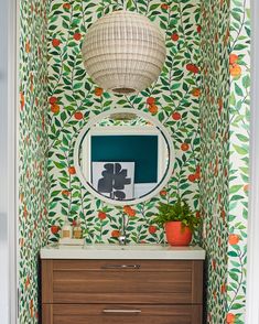 a bathroom with wallpaper and a mirror on the wall next to a wooden dresser