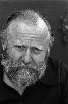 black and white photograph of an old man with a beard looking at the camera while wearing a polo shirt