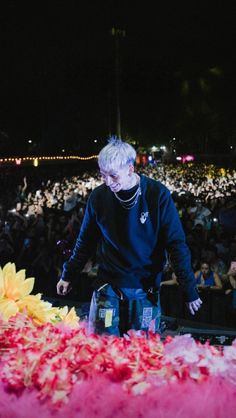 a man standing in front of a large group of people with flowers on the ground