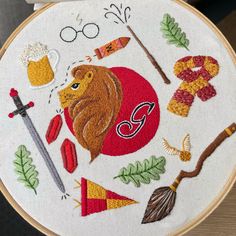 an embroidered hoop with various items on it, including a lion's head and other things