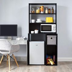 an office with a microwave, refrigerator and computer on the desk in front of it