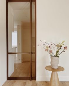 a vase filled with flowers sitting on top of a table next to a glass door