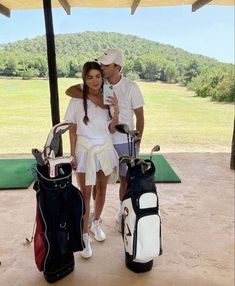 a man and woman standing next to each other with golf bags in front of them