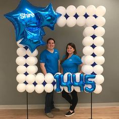 two people standing in front of a photo frame made out of balloons with the number 1005 on it