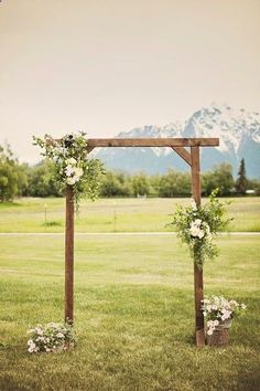 an outdoor ceremony setup with flowers and greenery on the grass in front of mountains