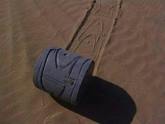 a piece of luggage sitting on top of a sandy beach next to a tire imprint in the sand