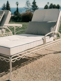 two white patio furniture sitting on top of a gravel field