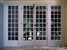 an empty room with double doors and brick flooring in front of the glass windows