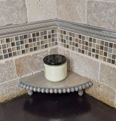 a white pot sitting on top of a wooden shelf in front of a tiled wall