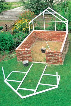 an outdoor garden area made out of bricks and plastic pipes, in the middle of a yard