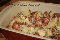 a red casserole dish filled with potatoes and grated cheese