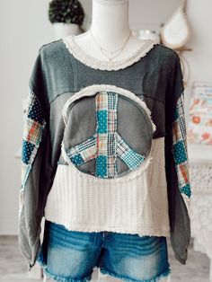 a woman's sweater with a peace sign on the front and patchwork patches on the back