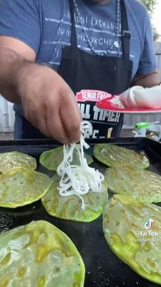 the man is cooking food on the grill with his hands and fingers are sprinkled with white sauce