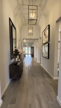 a long hallway with wood flooring and framed pictures hanging on the wall above it