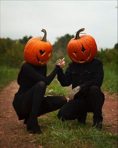 two people wearing pumpkin heads sitting on the ground