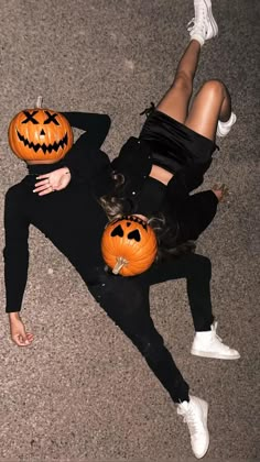 a woman laying on the ground with two pumpkins