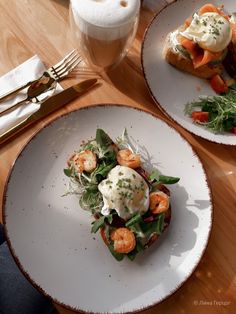 two white plates topped with food on top of a wooden table