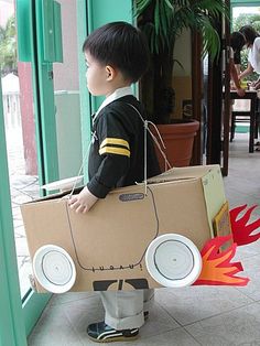 a young boy is dressed up as a cardboard car and holding a cardboard box with wheels on it