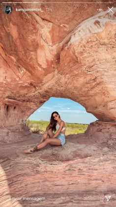 a woman sitting on the ground in front of a rock formation