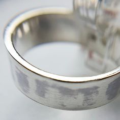 a close up view of a silver ring on a white surface with an object in the background