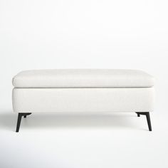 a white bench sitting on top of a wooden floor next to a gray wall and black legs