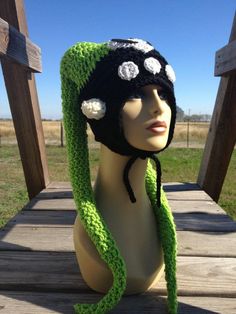 a mannequin head wearing a green and black hat with white flowers on it