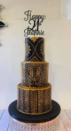 a three tiered cake is decorated with black and gold designs on the bottom layer