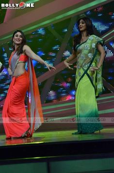 two women in sari dancing on stage with one holding the other's hand