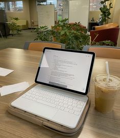 an open laptop computer sitting on top of a wooden table next to a cup of coffee