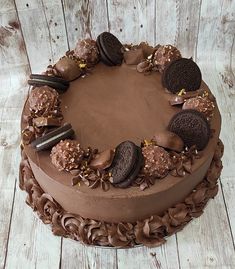 a chocolate cake with cookies and oreo cookies on top, sitting on a wooden table