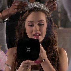 a woman wearing a tiara looking at her cell phone